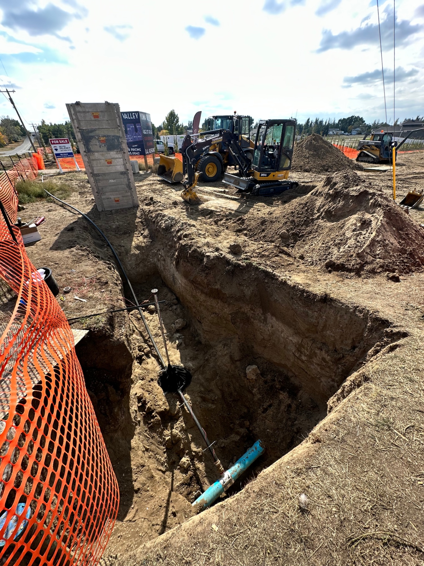 Avara crew trenching for utility service installation with mini excavator and skid steer on a new development site